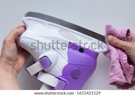 Woman hands wipe skate blades dry with rag on white background. Concept how to remove and care
