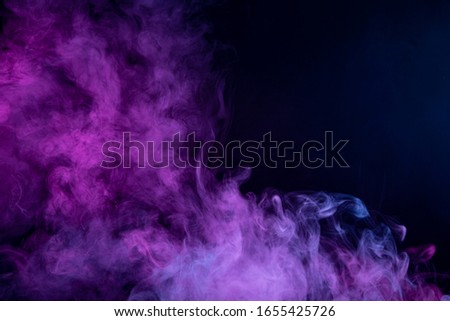 Abstract art  pink and blue colored smoke on black isolated background. Stop the movement of multicolored smoke on dark background
