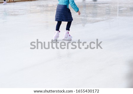 Little girl skates on an ice rink. Legs close up.