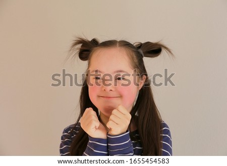 Cute smiling down syndrome girl on the grey background