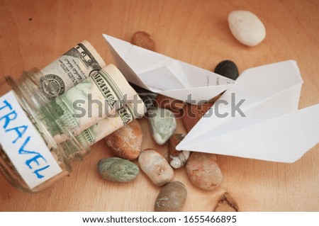 
Paper boat and paper airplane as a symbol of travel. Jar of money for travel. We save up for travel.