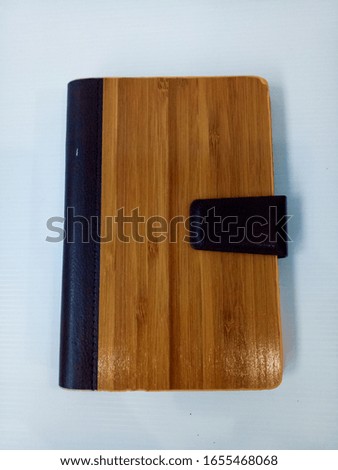 Notebook with wooden patterns Placed on a white floor.