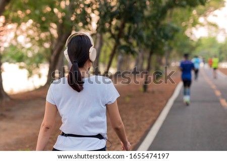 Woman exercise walking in the park listening to music with headphone Royalty-Free Stock Photo #1655474197
