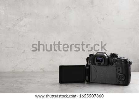 Modern camera on light grey stone table, space for text. Video production industry