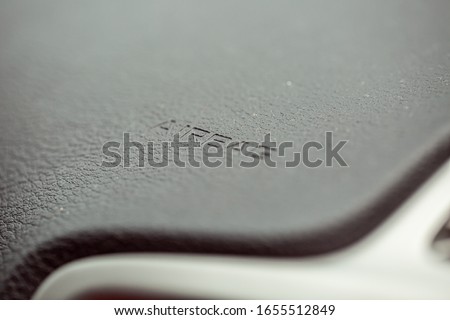 Inscription on the panel of the vehicle airbag. background of grey textured plastic close-up