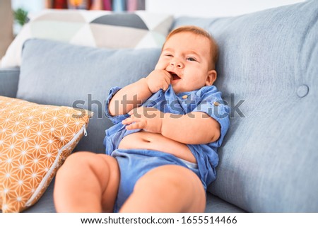 Adorable baby lying down on the sofa at home. Newborn crying and screaming