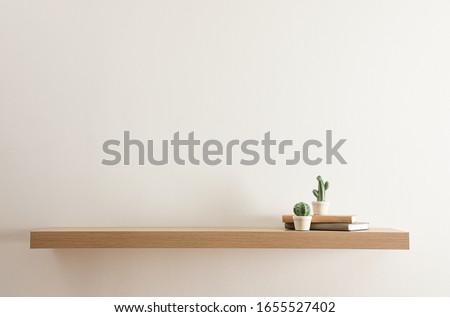Wooden shelf with books and decorative cactuses on light wall Royalty-Free Stock Photo #1655527402