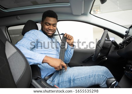 Own Car. African American Man Putting On Seat Belt Sitting In Auto In Dealership Store. Selective Focus Royalty-Free Stock Photo #1655535298
