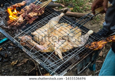 Barbecued fresh whole chicken outdoors in the forest Royalty-Free Stock Photo #1655536696