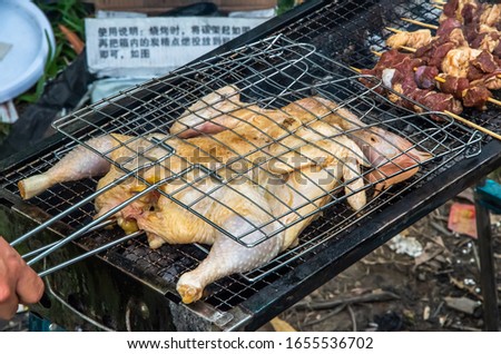 Barbecued fresh whole chicken outdoors in the forest Royalty-Free Stock Photo #1655536702
