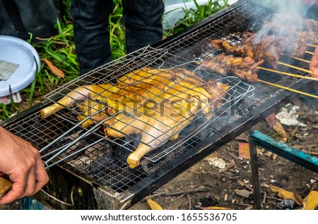 Barbecued fresh whole chicken outdoors in the forest Royalty-Free Stock Photo #1655536705