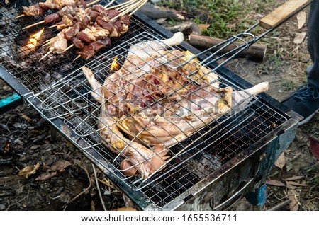 Barbecued fresh whole chicken outdoors in the forest Royalty-Free Stock Photo #1655536711