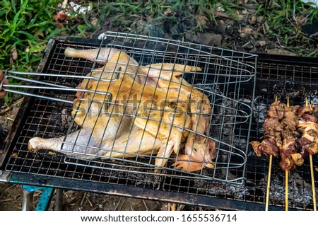 Barbecued fresh whole chicken outdoors in the forest Royalty-Free Stock Photo #1655536714