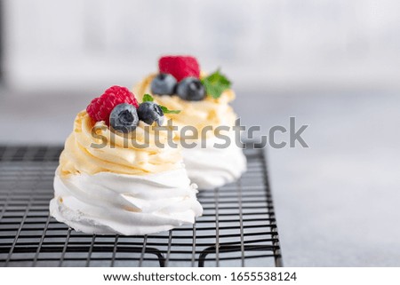 Delicious Pavlova cake with whipped cream and fresh berries on the cooling rack. Selective focus - Image