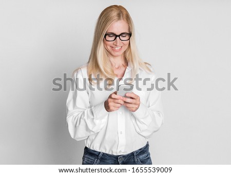Business Application. Happy Middle-Aged Businesswoman Texting On Mobile Phone Isolated Over Gray Wall. Free Space