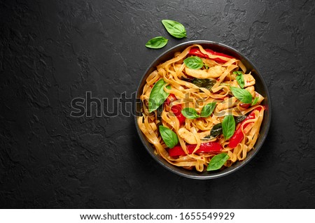 Thai Drunken Noodles or Pad Kee Mao in black bowl at dark slate background. Drunken Noodles is thai cuisine dish with Rice Noodles, Chicken meat, Basil, sauces and vegetables. Thai Food. Copy space Royalty-Free Stock Photo #1655549929