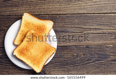 Background with slices of toast bread and old wooden table Royalty-Free Stock Photo #165556499