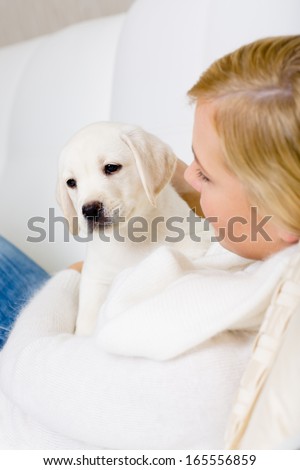 Close up of woman in white sweater embracing white white puppy