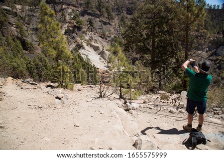 hiker tourist making smartphone pictures of a moonscape or eroded hoodoo in the Canary pine forest landscape