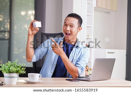attractive asian businessman showing credit card debit card to purchase and happy shopping concept. consumer experience