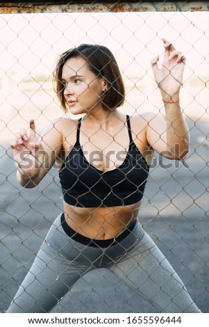 young attractive girl in sportswear on the Playground doing sports exercises in the summer at sunset