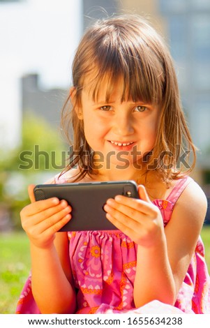 Psychological image of cute little girl addicted to likes: Social networks feeds her neediness. Close up sad child with mobile smart phone. Negative emotion and emotional addiction concept. 
