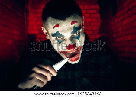 Close-up portrait of a joker man. Stock photo makeup joker in a horror room.