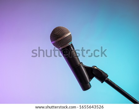 Classic microphone on concert stand on lilac blue background
