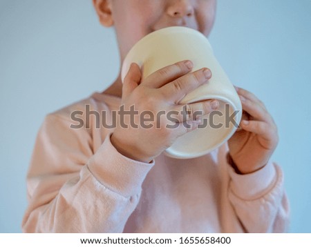 handsome blond boy with a fashionable haircut holds a light tea cup on a purple-blue background