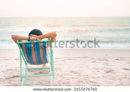 solo man travel relax and sit on beach chair see to beach and sunset background on summer season
