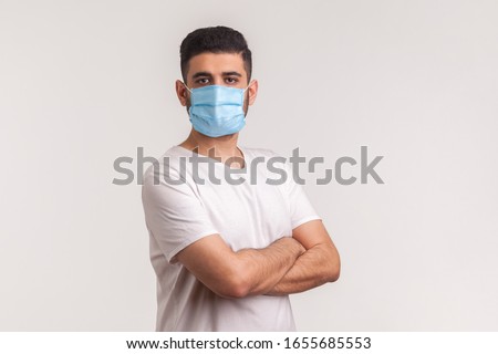 Effective protection against coronavirus. Man holding hands crossed and wearing hygienic mask to prevent infection, respiratory illness such as flu, 2019-nCoV, Covid-19. indoor studio shot, white back Royalty-Free Stock Photo #1655685553