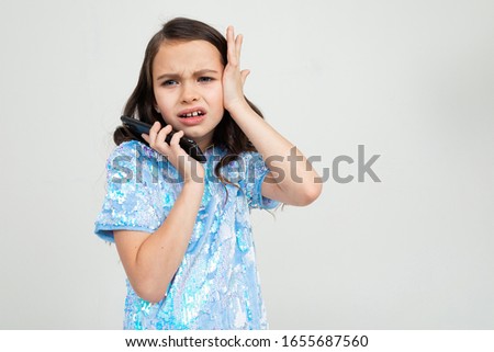 indignant teenager girl carefully talking on the phone in an interlocutor and holding her head on a white background with copy space