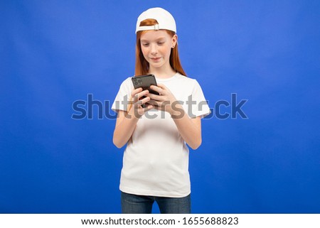 attractive red-haired teenager girl in a white T-shirt communicates in instant messengers