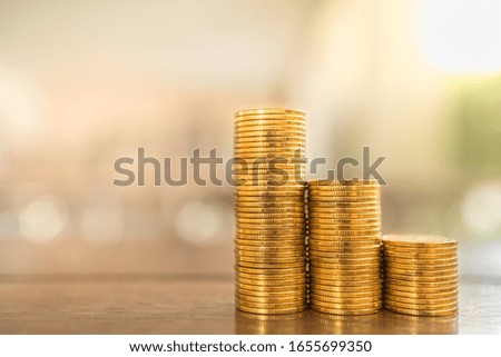 Business, Money, Finance, Security and Saving Concept. Close up of three stack of gold coins on wooden table under sunlight with copy space.