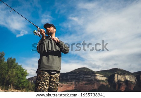 fisherman enjoy hobby with fishing rod, person catch fish on background mountain, holiday relaxation fishery concept