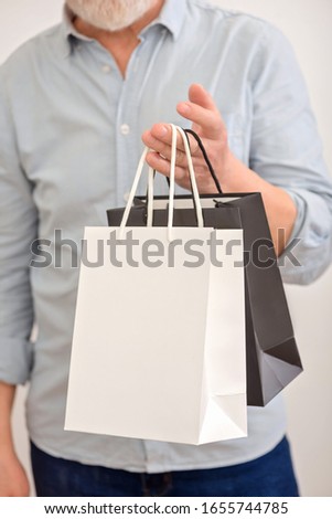 Senior man holds bag. Senior man courier. Online shoping. Post retirement job