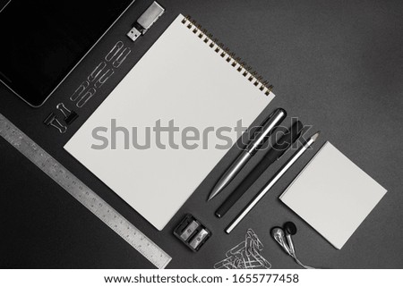 Office supplies on a black background. Notepad, ruler, pencil, pens, paper clips, sharpener. Working space, top view. Place under the text.