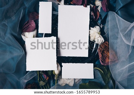 Wedding invitation mockup with old cracked black plate, roses, papers on silk blue background. Top view, flat lay. Wedding stationary. Perfect for presentation of your invitation, menu, greeting cards