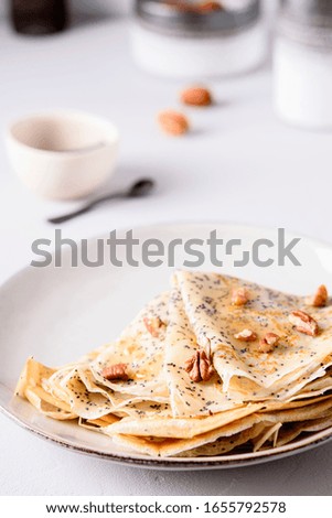 Crepes with poppy seed served with honey and pecans on grey background. Maslenitsa holiday. Selective focus