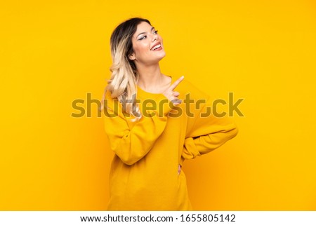 Teenager girl isolated on yellow background pointing to the side to present a product