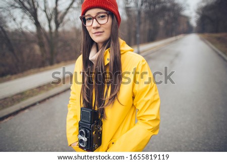 Portrait of hipster girl in raincoat with vintage twin-lens reflex camera. Millennial girl portrait with medium format camera