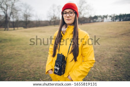 Photographer girl in yellow raincoat. Millennial girl photographer rainy day portrait