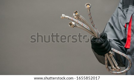 Water hose in plumber hands close up over gray background with copy space.
