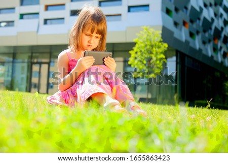 Psychological portrait of cute little girl addicted to likes: Social networks feeds her neediness. Portrait of sad child with mobile smart phone. Negative emotion and emotional addiction concept. 