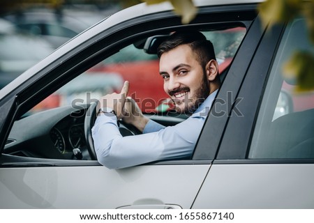 Young man smiling at the camera while driving Royalty-Free Stock Photo #1655867140