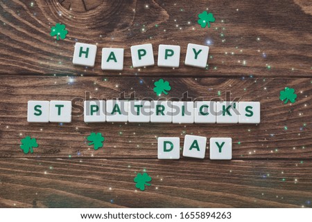 Letters Happy St.Patrick's Day on wooden background, greeting card, paper shamrocks decoration