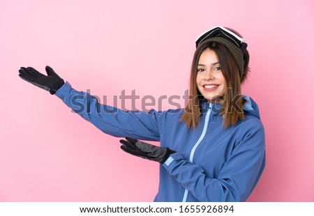 Young skier woman over isolated pink background extending hands to the side for inviting to come