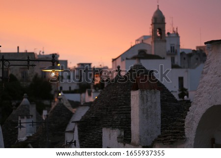 Cityscape of Alberobello; the trulli UNESCO world heritage town with unique stone walls, coned roofs, whitewashed housed during sunset evening, 
