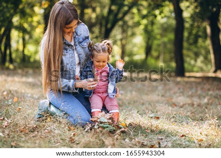Young mother with her little daughter in an autumn park
