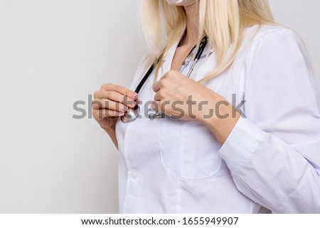 Unrecognizable woman doctor physiotherapist in white uniform with stethoscope on white background. Royalty-Free Stock Photo #1655949907